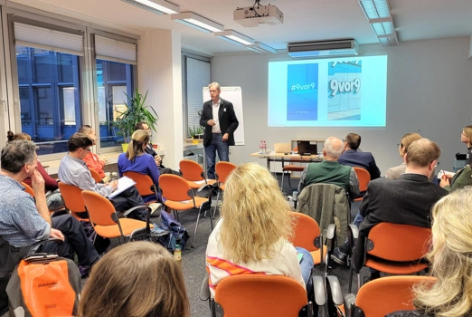 Gäste sitzen im Vortragsraum und blicken zum Vortragenden Prof. Dr. Wald.