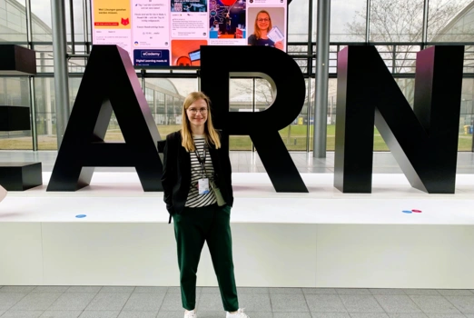 Eine junge Frau steht vor einer Buchstaben-Installation auf der Messe Learntec.