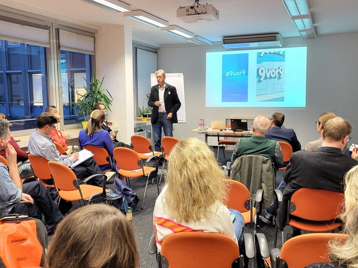 Gäste sitzen im Vortragsraum und blicken zum Vortragenden Prof. Dr. Wald.